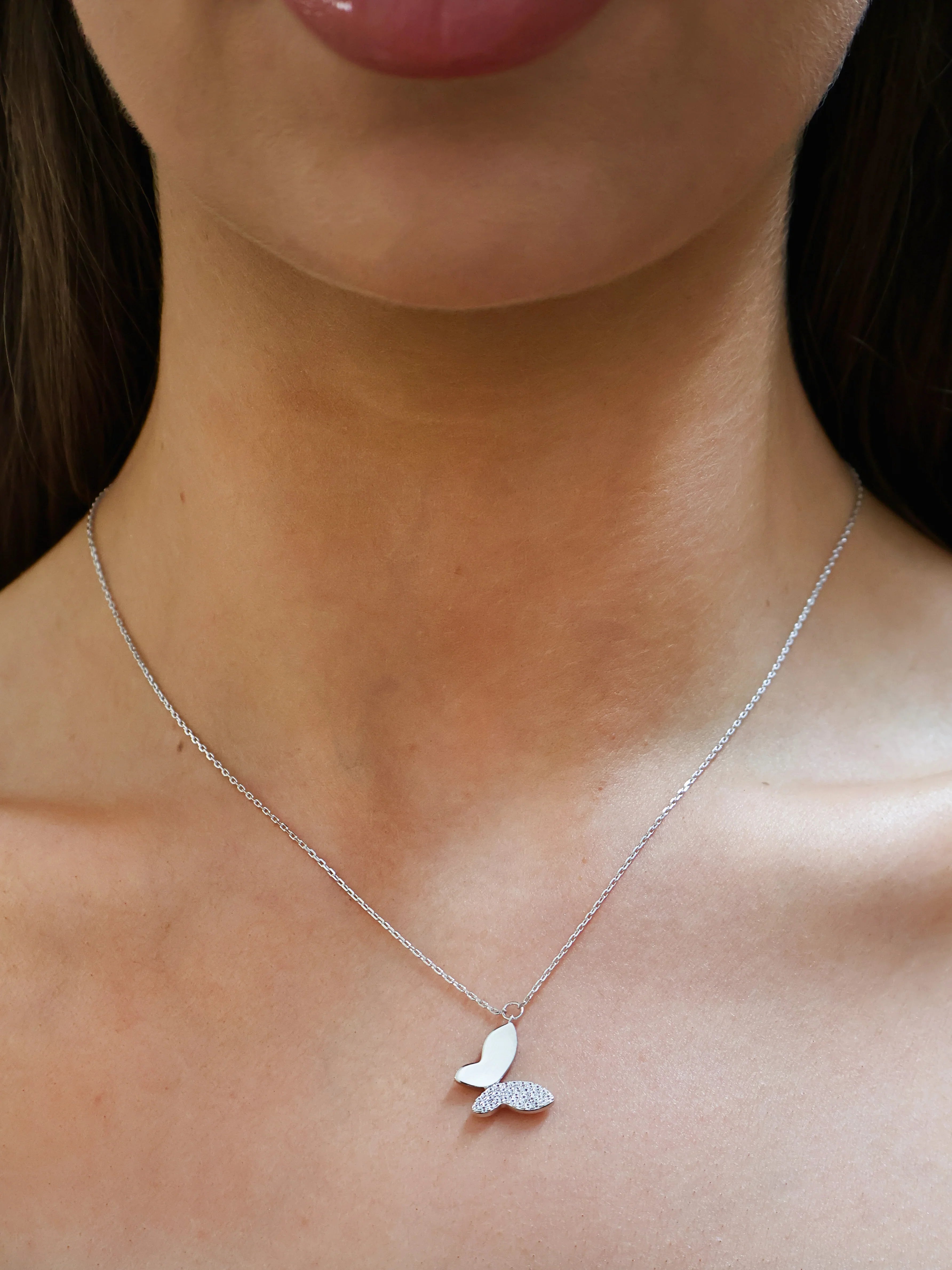Silver butterfly pendant necklace with one wing encrusted with sparkling crystals on chain