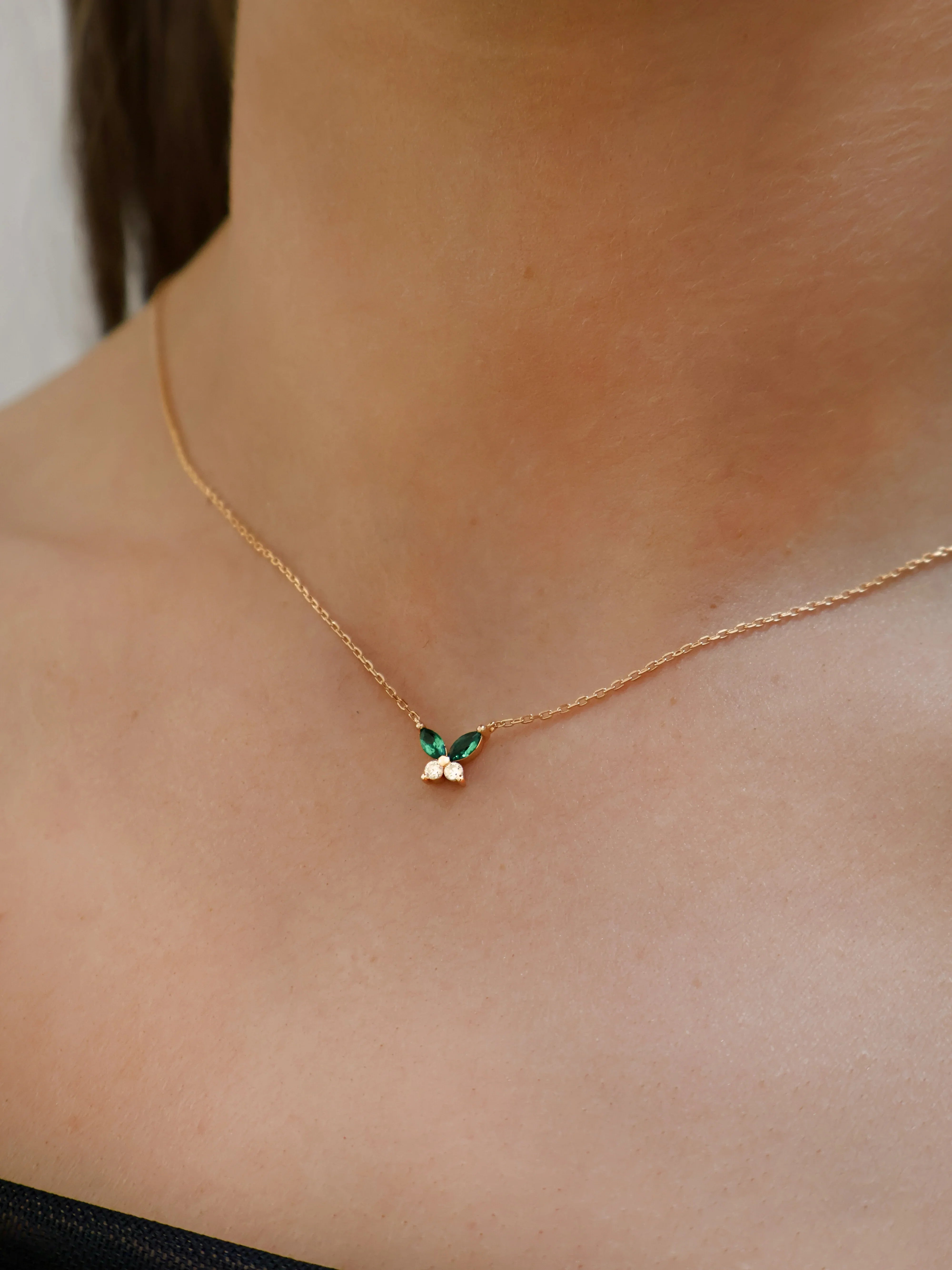 Gold necklace with a green gemstone pendant on a person's neck