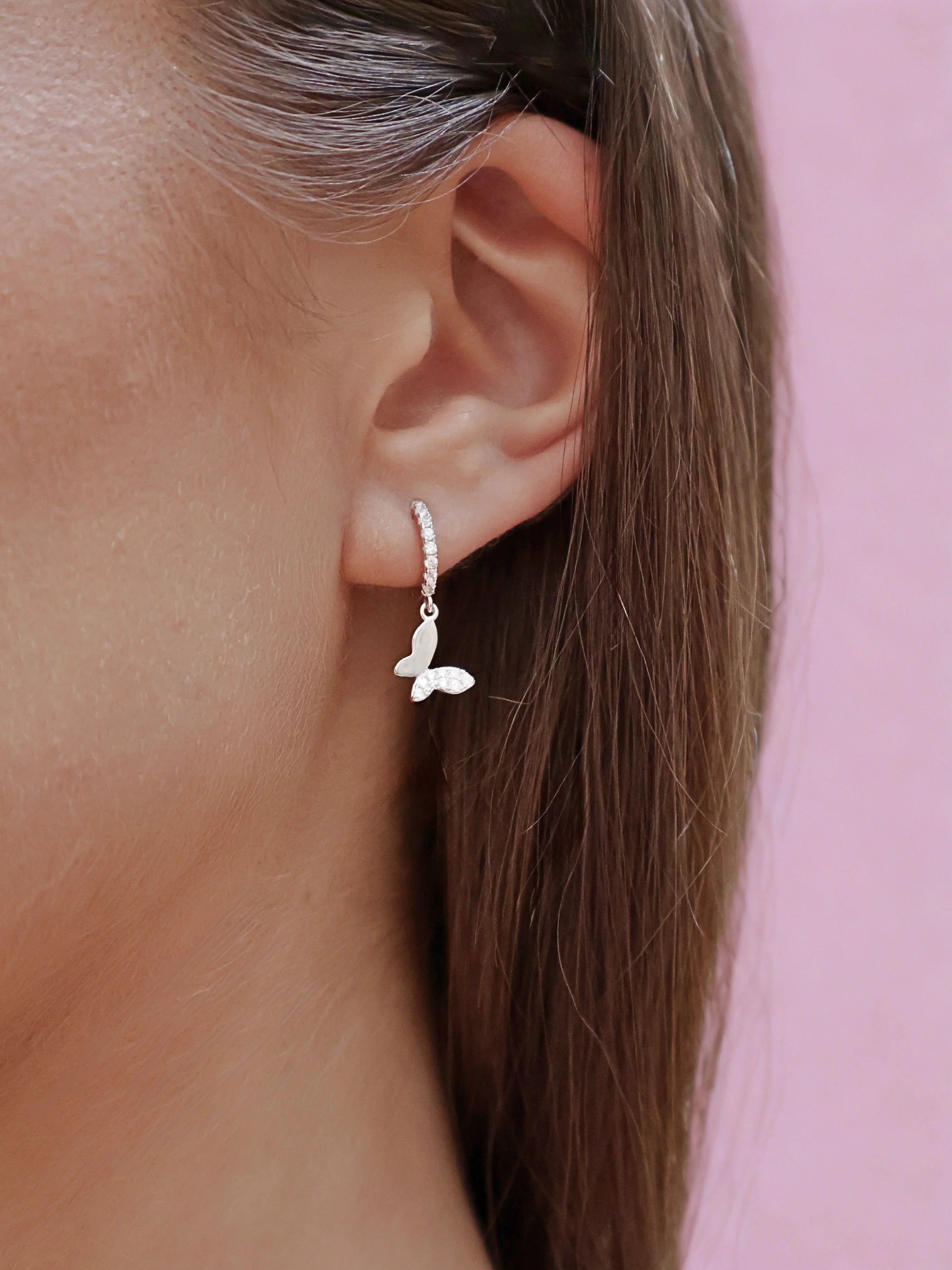 Silver hoop earring with clear crystals and a dangling butterfly charm featuring crystal accents