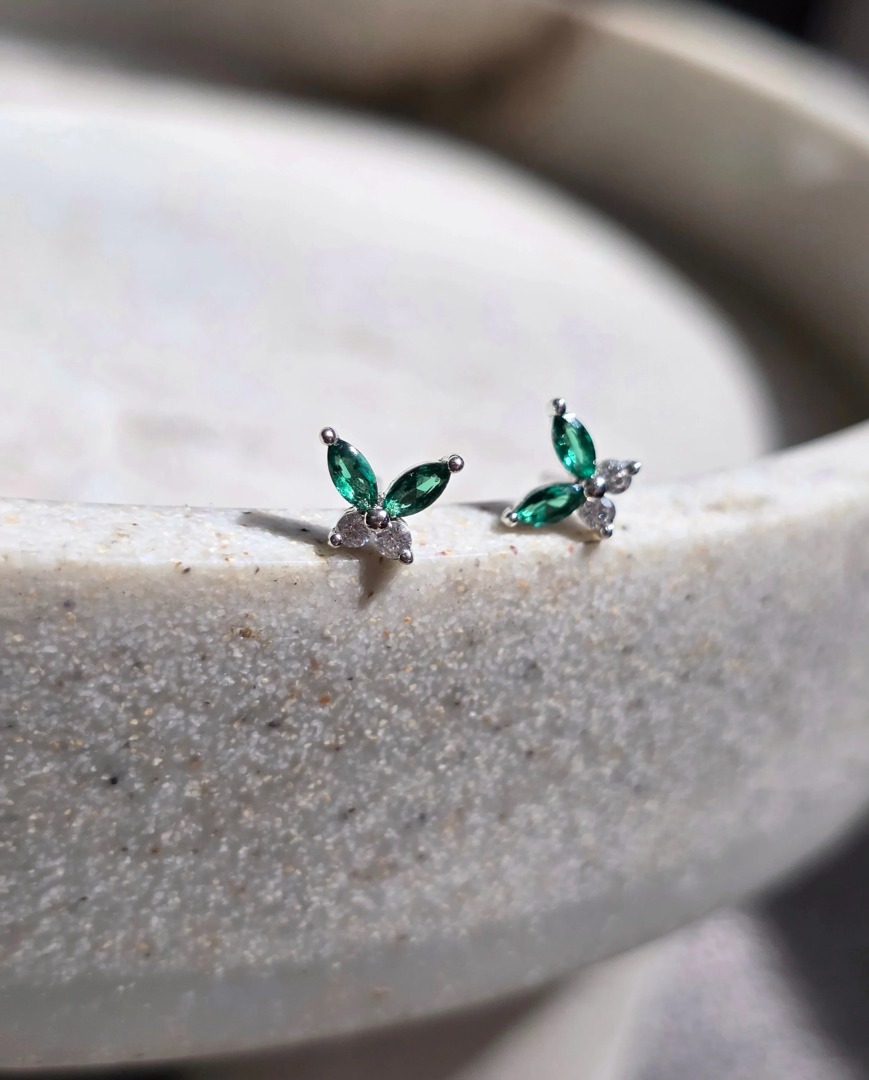 Pair of green gemstone earrings on a textured surface- a pair