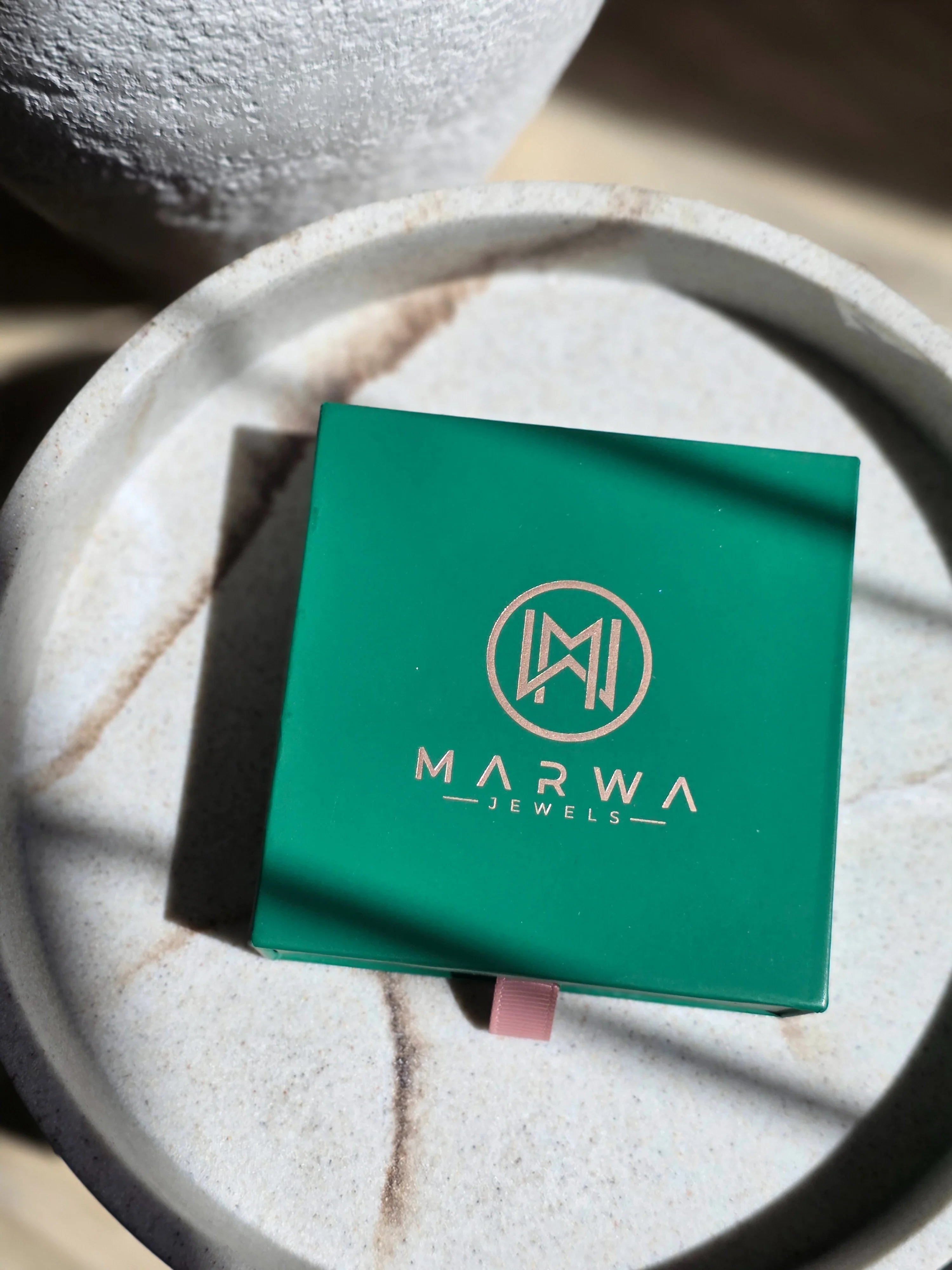 Green jewelry box with 'Marwa Jewels' logo on a textured surface