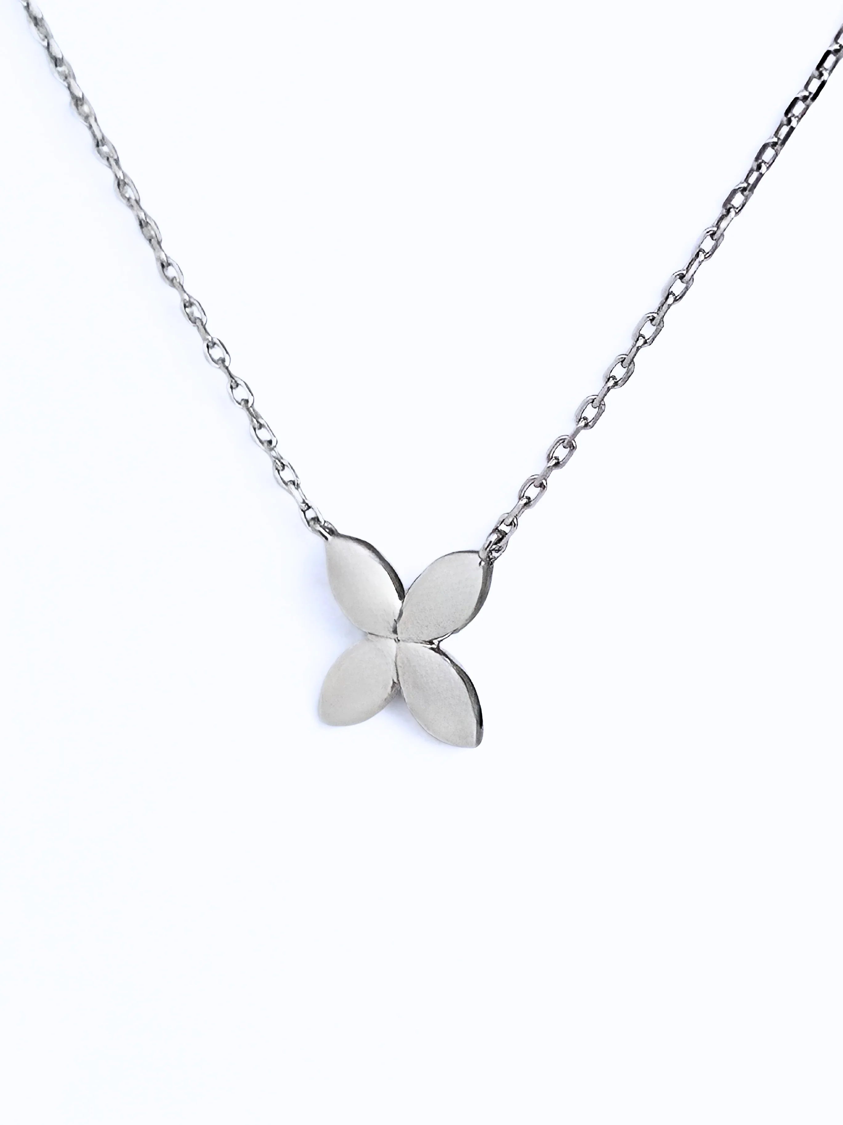 Silver flower-shaped pendant on a chain against a white background- front