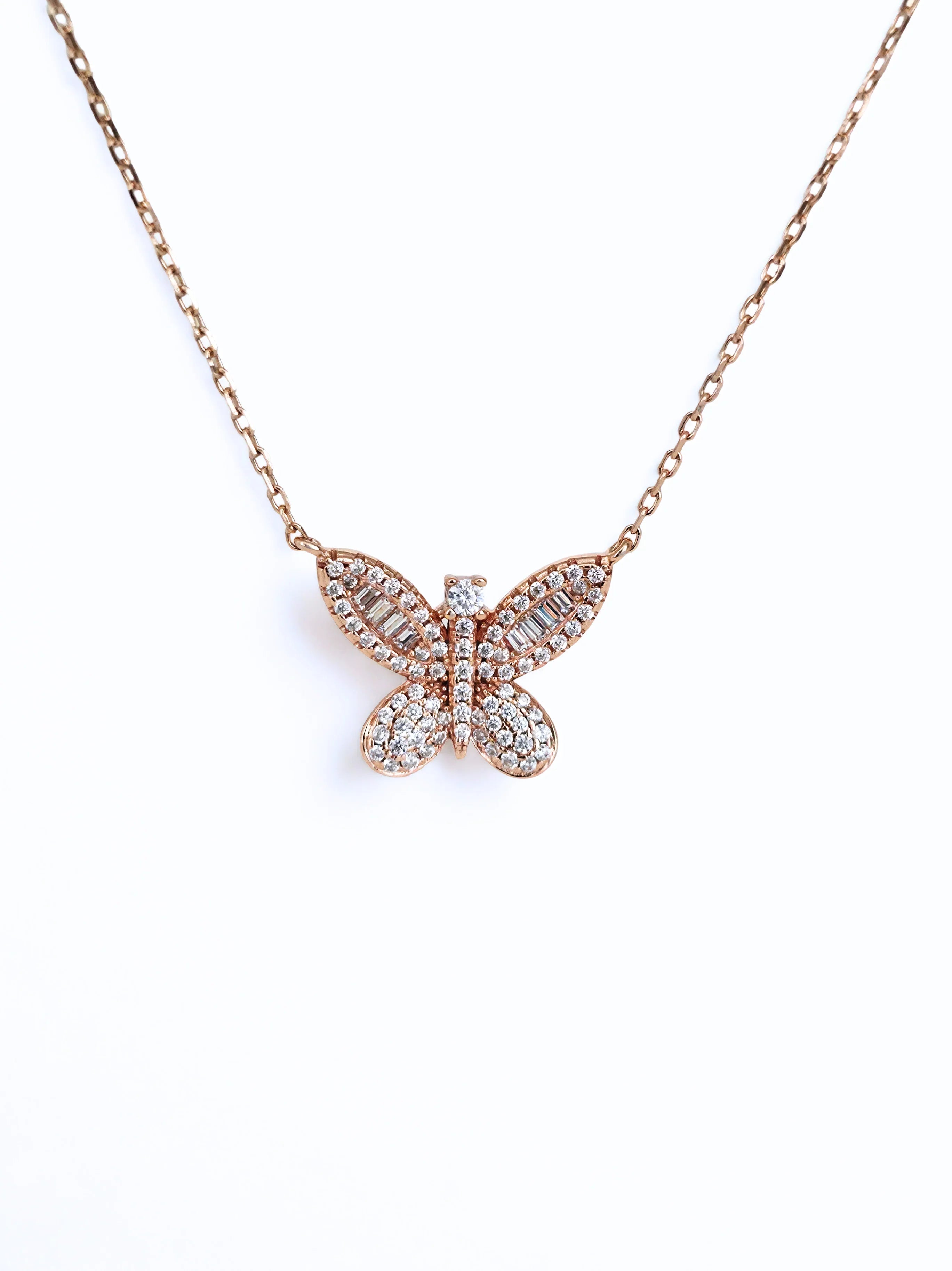 Butterfly-shaped necklace with rose gold and clear stones on a white - further background