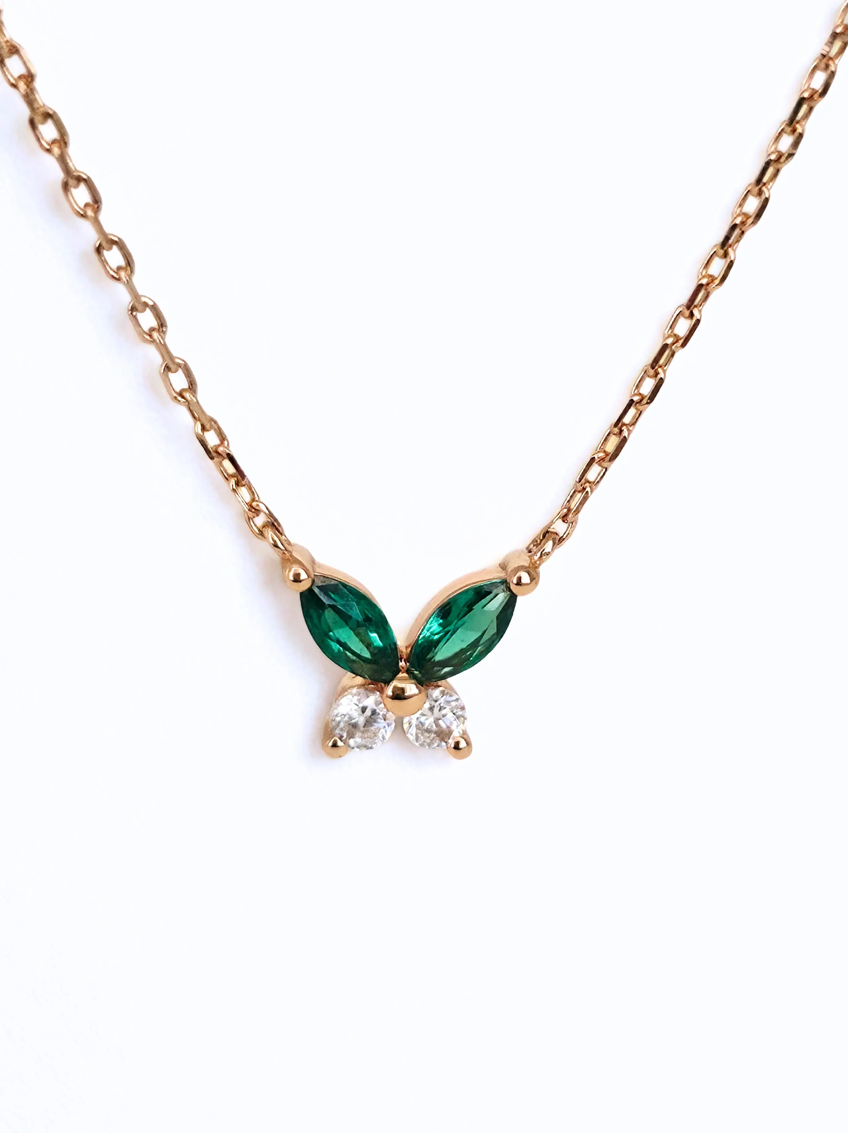 Gold necklace with green gemstone butterfly pendant on a white - background front