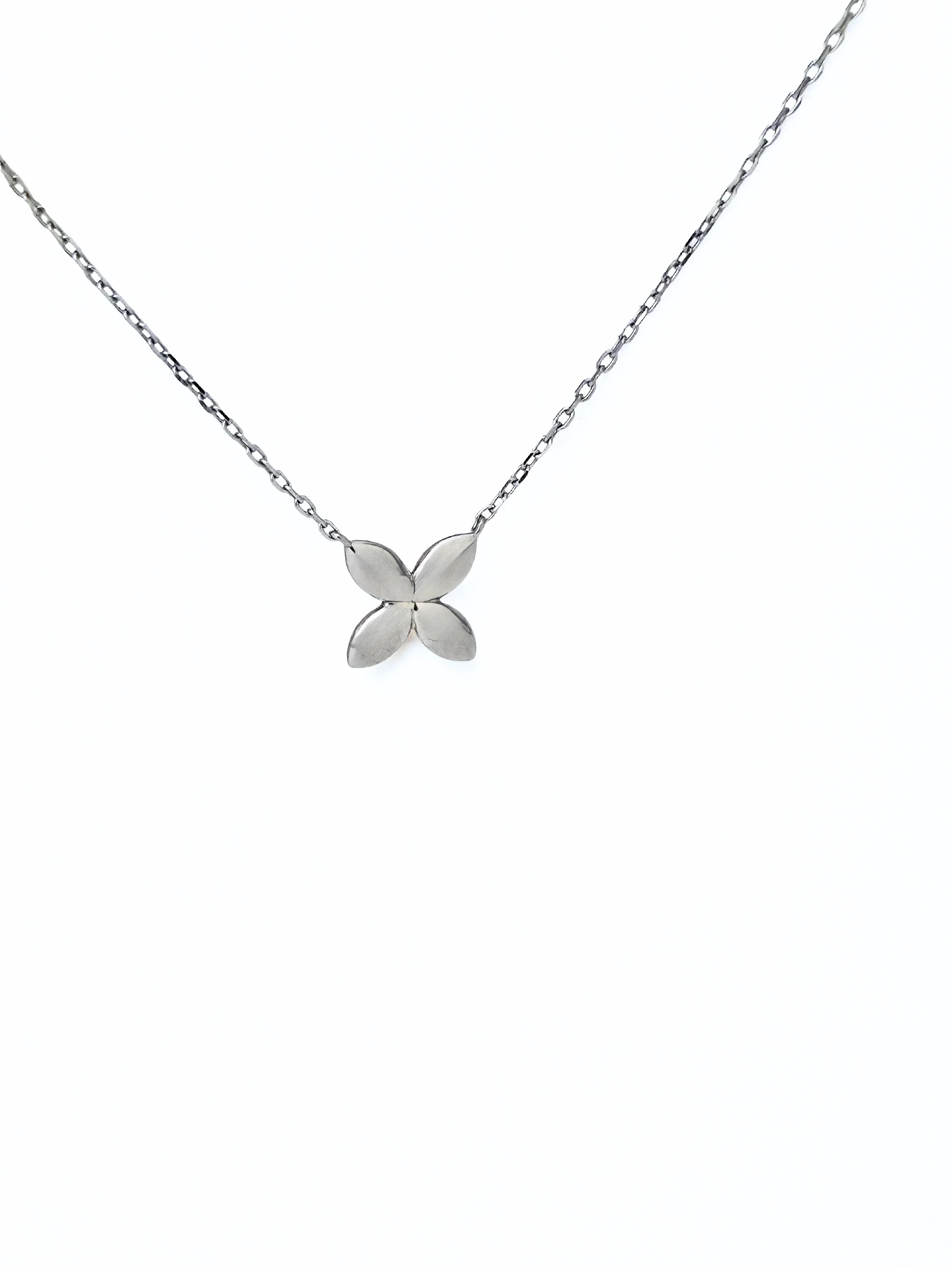 Silver flower-shaped pendant on a chain against a white background- front