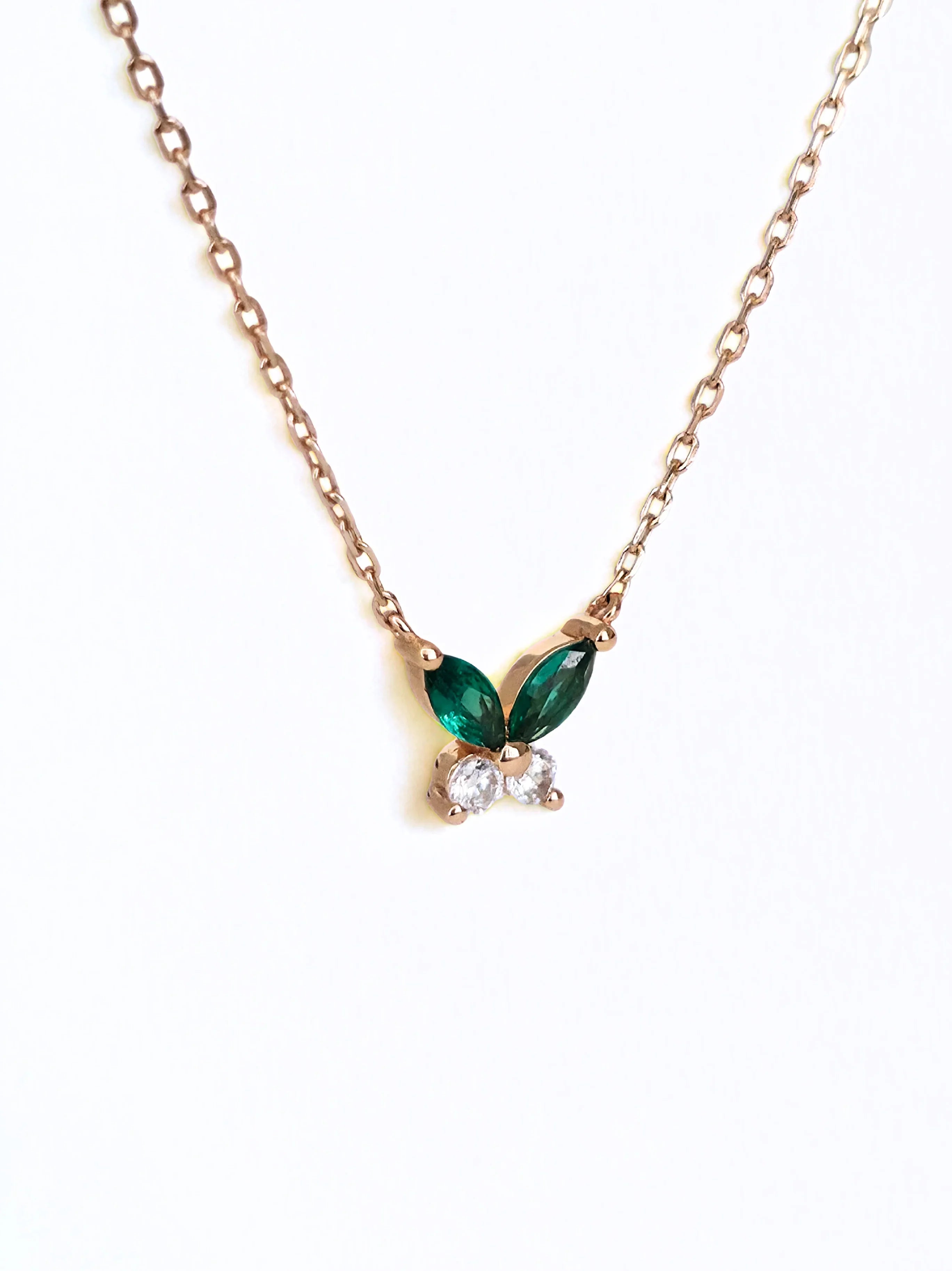 Gold necklace with green leaf-shaped pendant on a white background- side ways