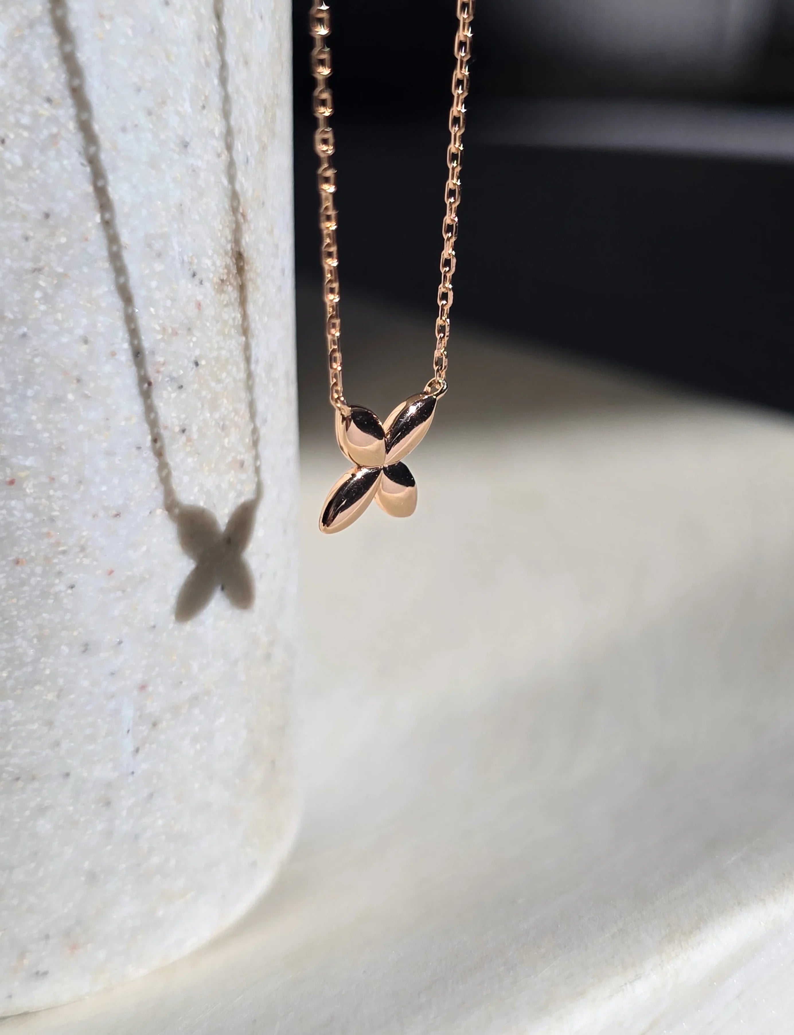 Rose gold necklace with a leaf pendant on a light background- side ways