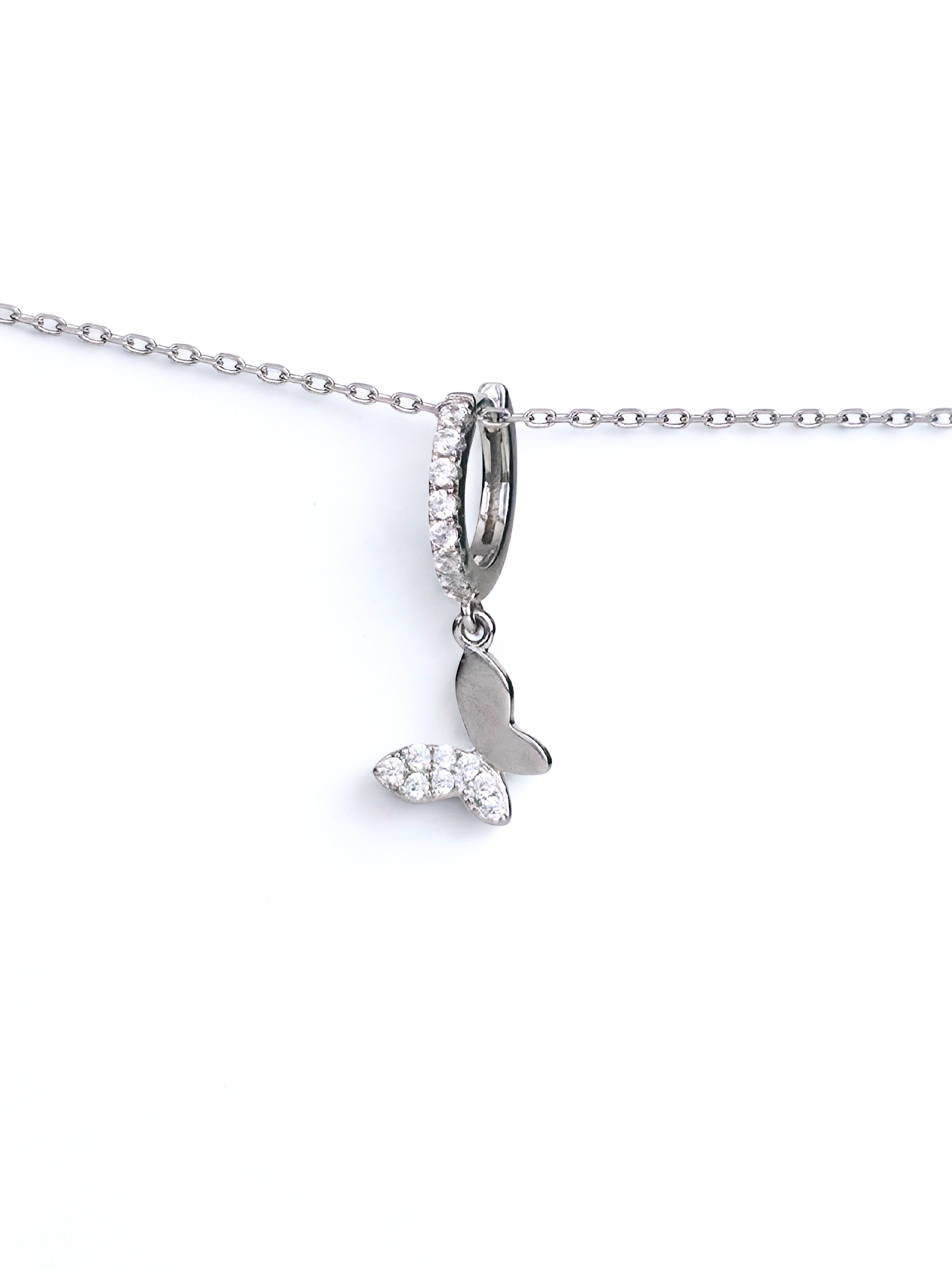 Silver necklace with a butterfly huggieson a white background- further