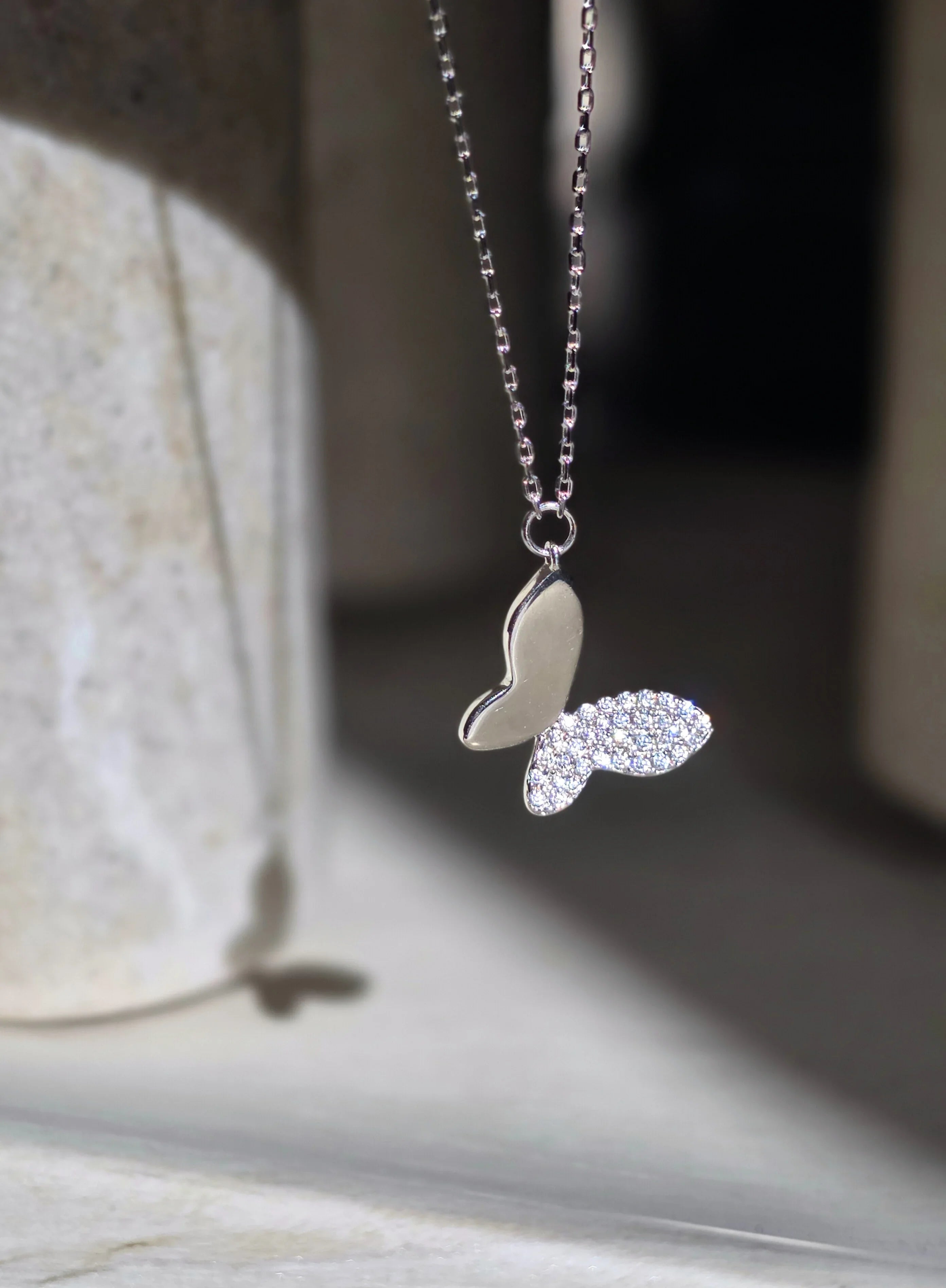 Silver butterfly necklace with diamond accents on a texturedbackground- chic butterfly necklace silver - front