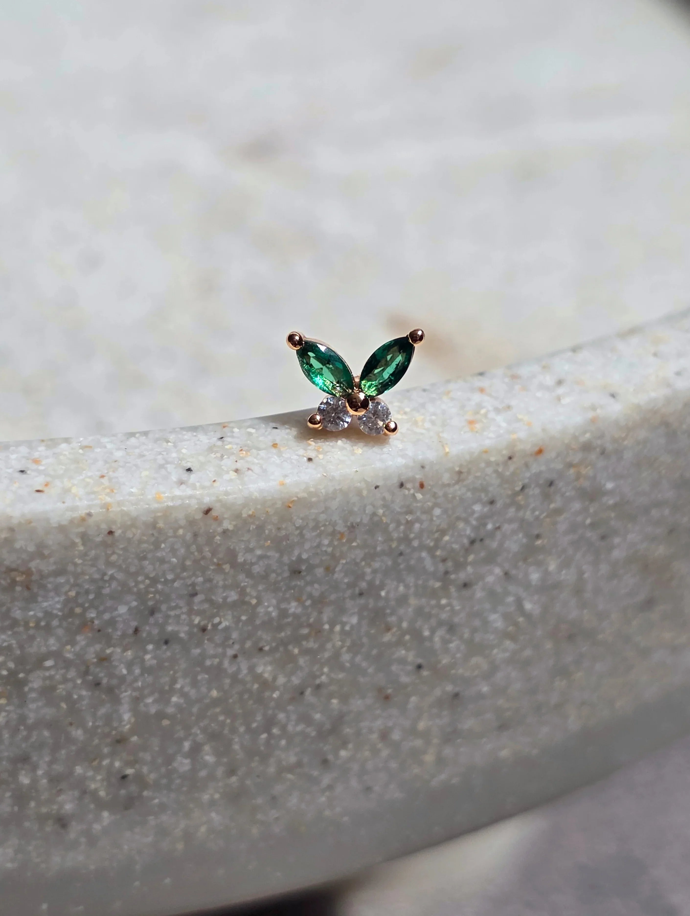 Petite butterfly earrings rose gold, on a textured background , front