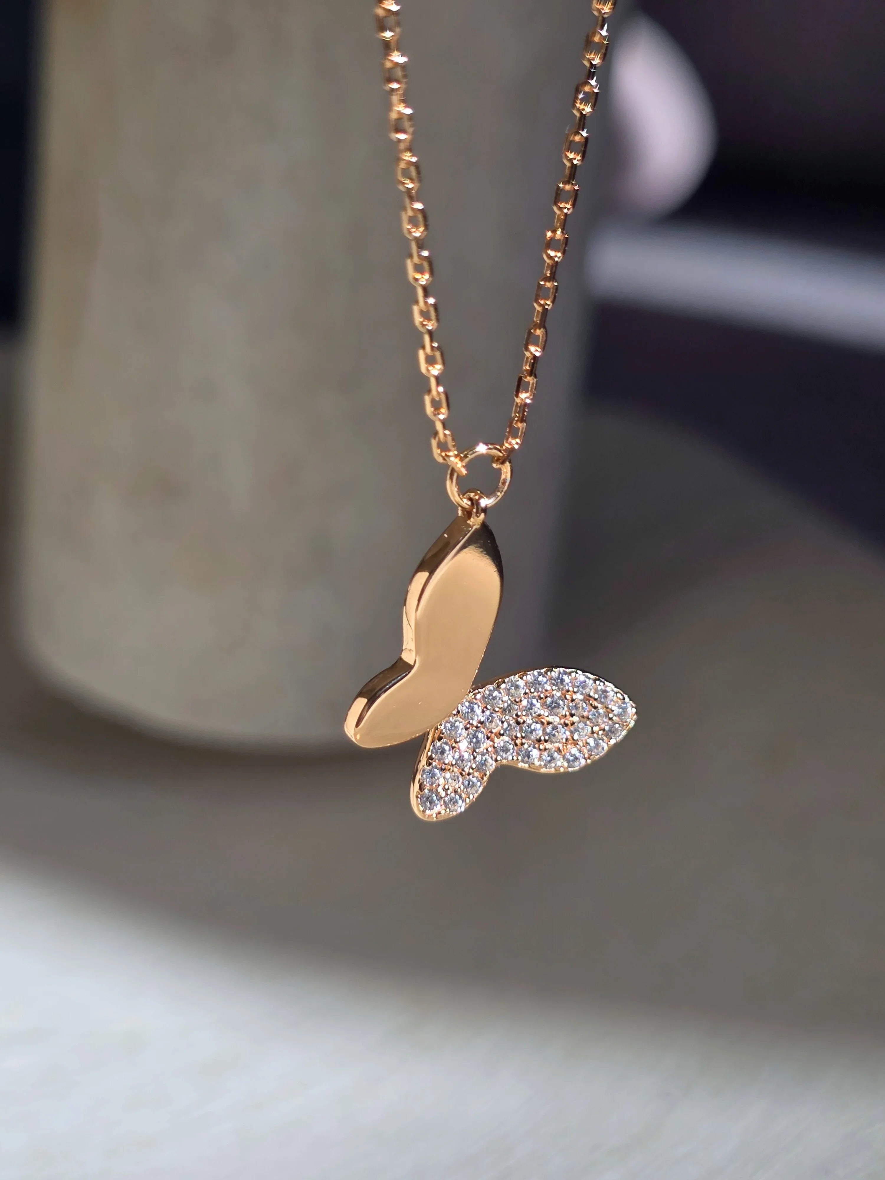 Gold necklace with a heart-shaped pendant on a neutral background- side ways