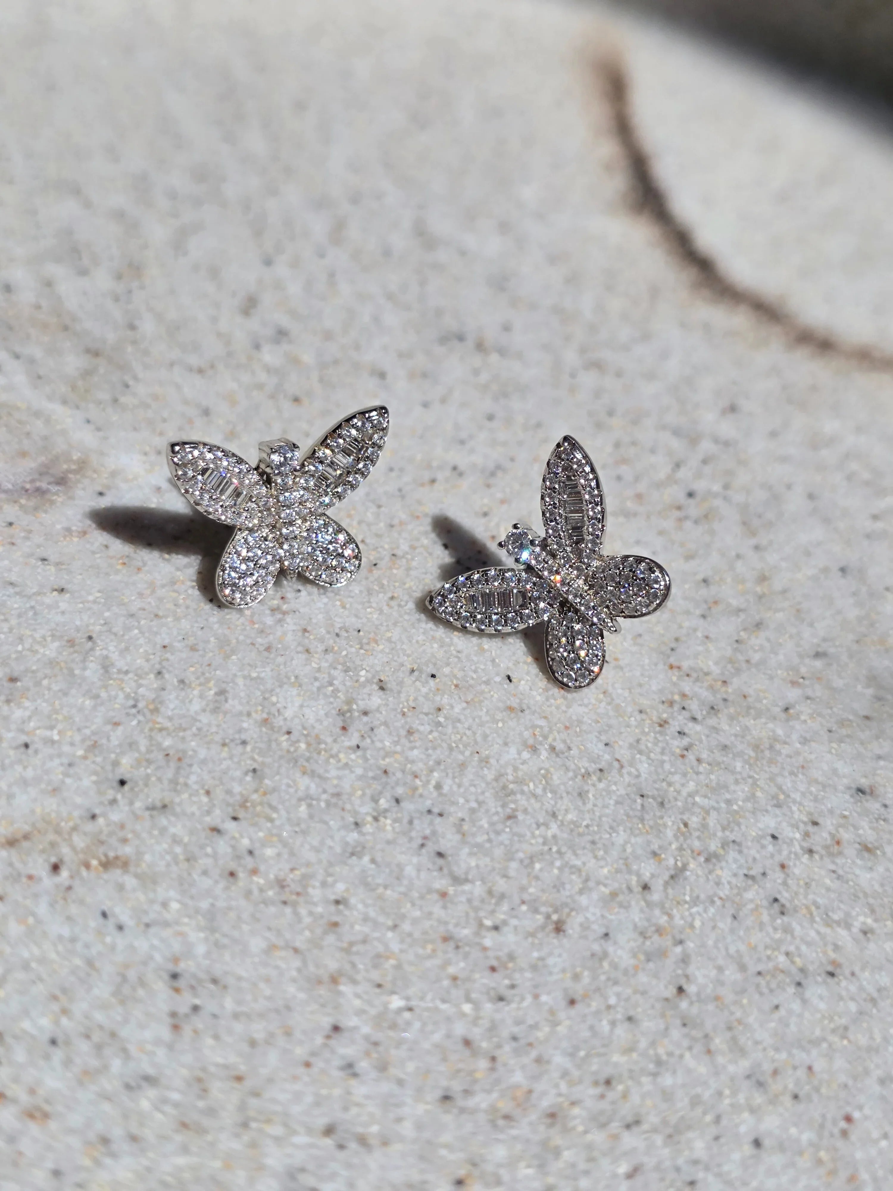 Butterfly-shaped earrings with gemstones on a textured surface- pair
