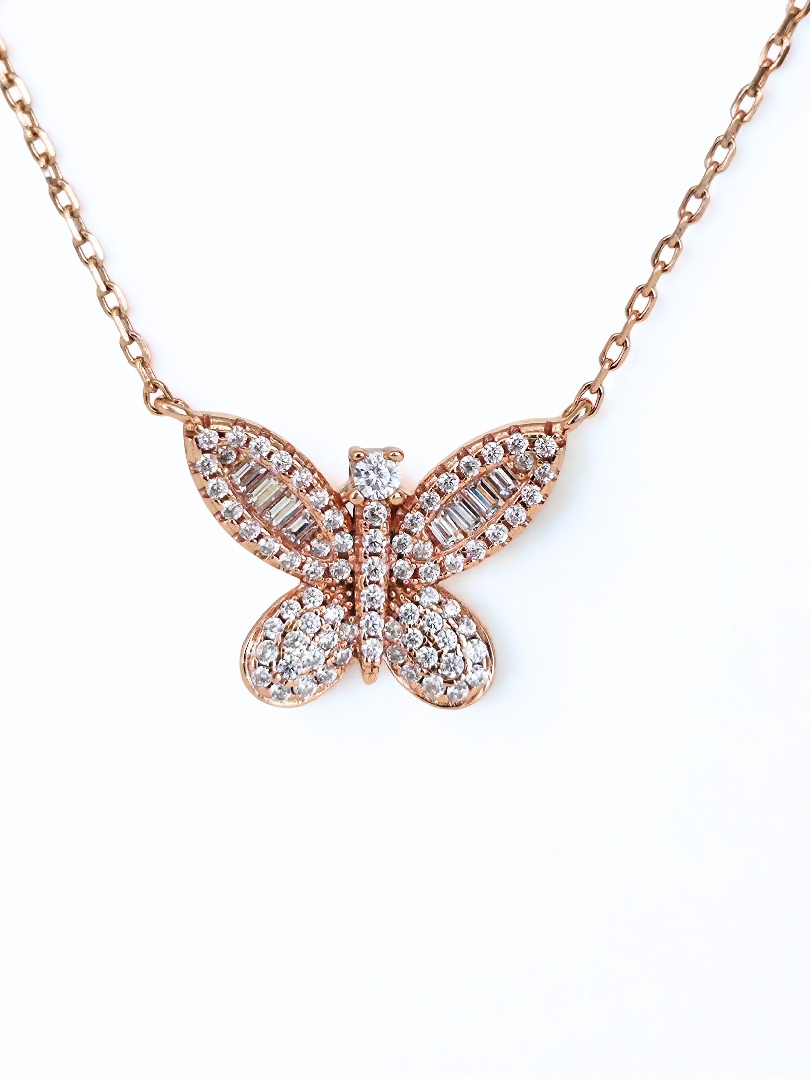 Butterfly-shaped necklace with rose gold and clear stones on a white - further background