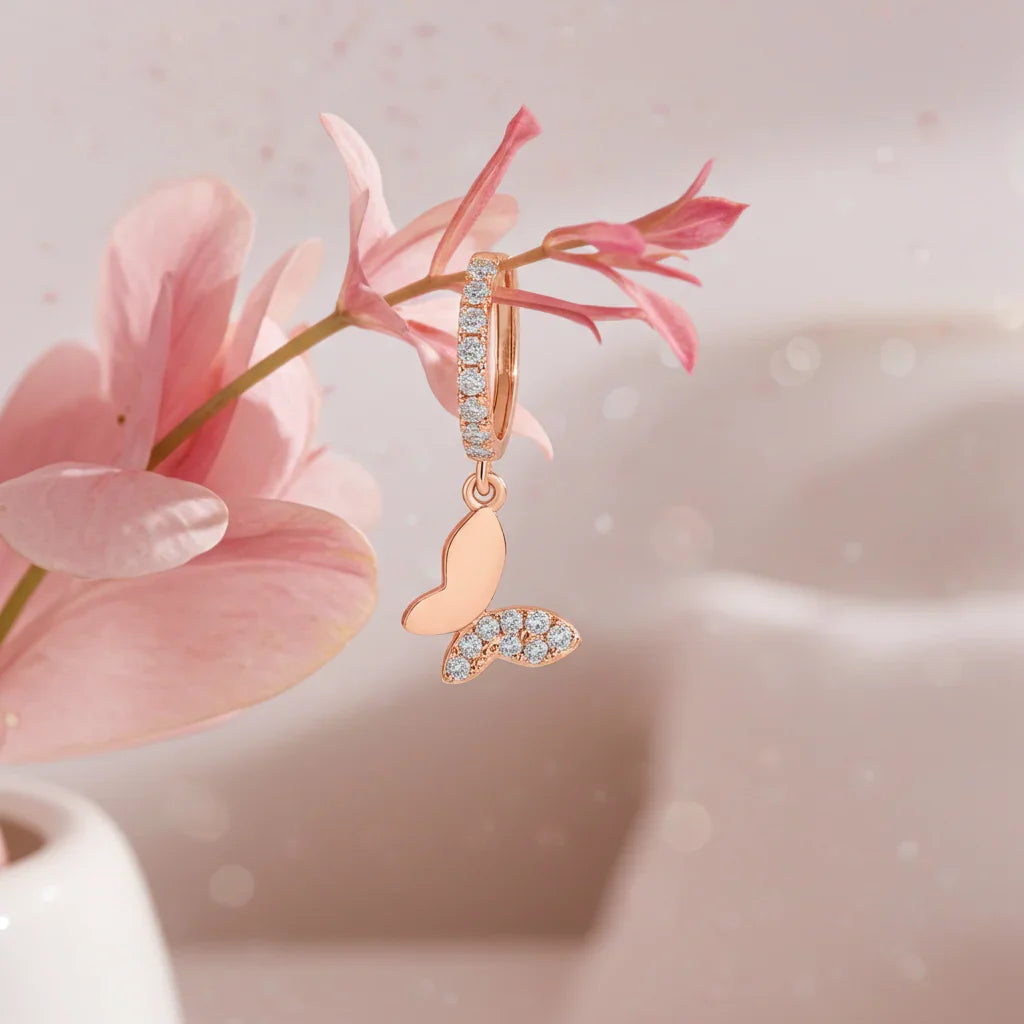 Rose gold butterfly huggie drop earring with sparkling stones hanging on pink flower branch