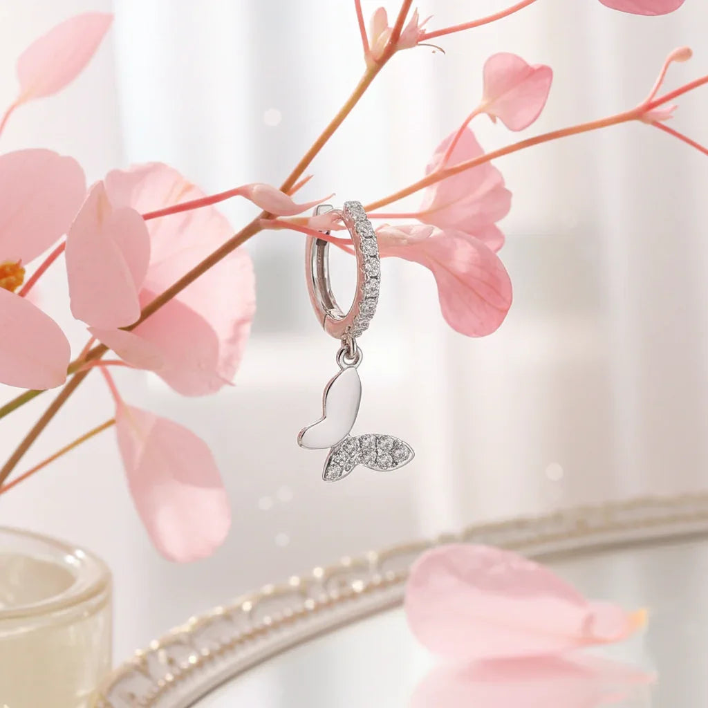 Silver butterfly huggie drop earring with white enamel and crystals hanging on delicate pink flowers, elegant jewelry