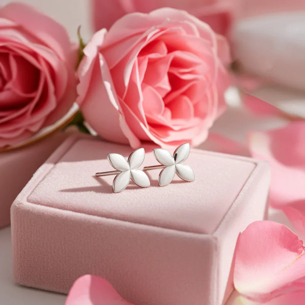 Minimalist silver flower stud earrings on pink velvet box with soft pink roses and petals