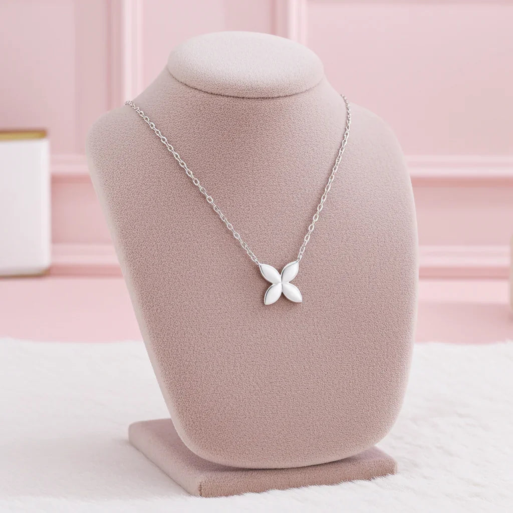 Minimalist silver butterfly necklace on pink jewelry display stand with soft pink background