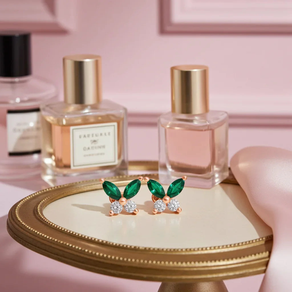 Green gemstone earrings on a small round table with perfume bottles in the background.