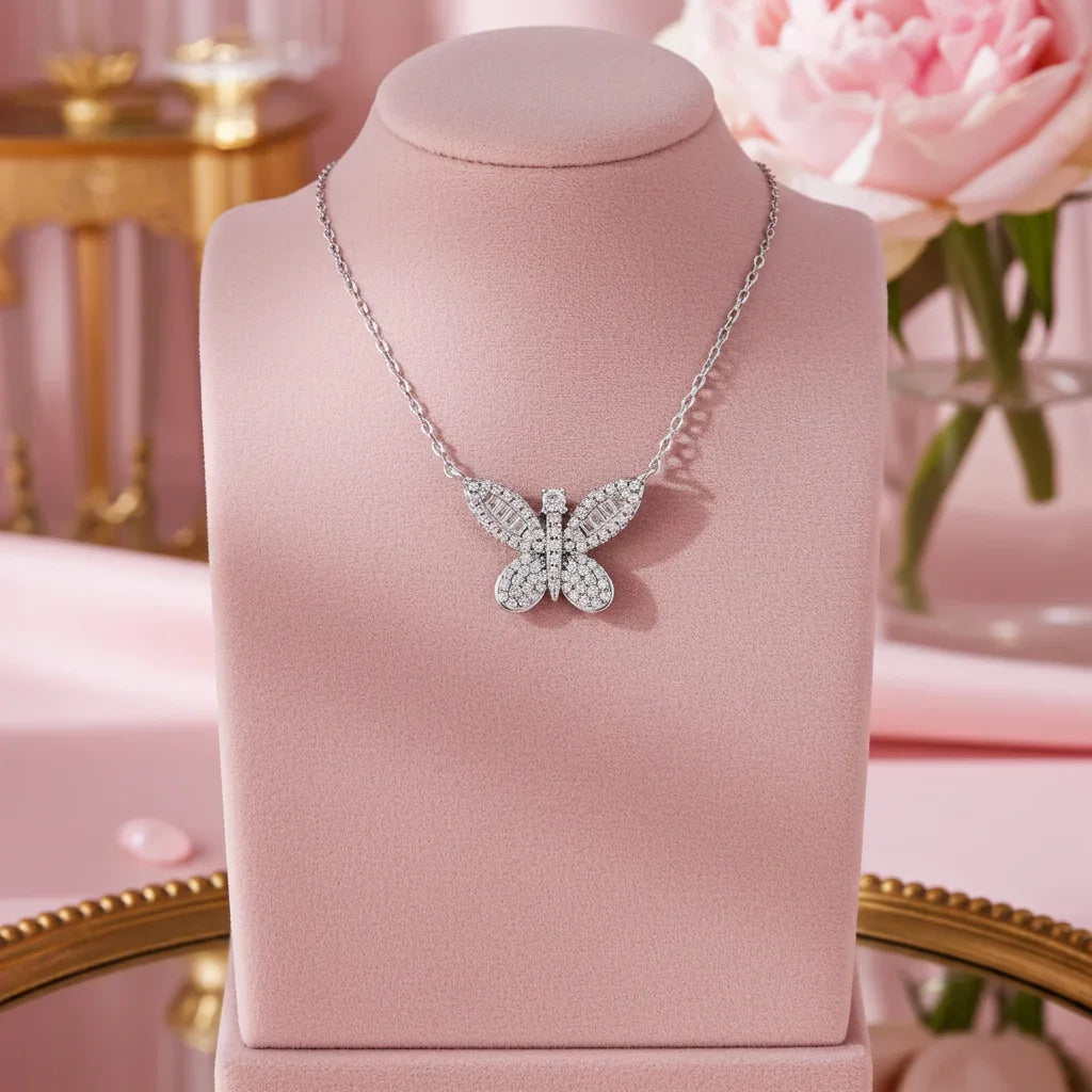 Silver butterfly pendant necklace with sparkling crystals displayed on pink velvet stand with soft floral background