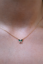 Butterfly-shaped necklace with green gemstones on a person's neck