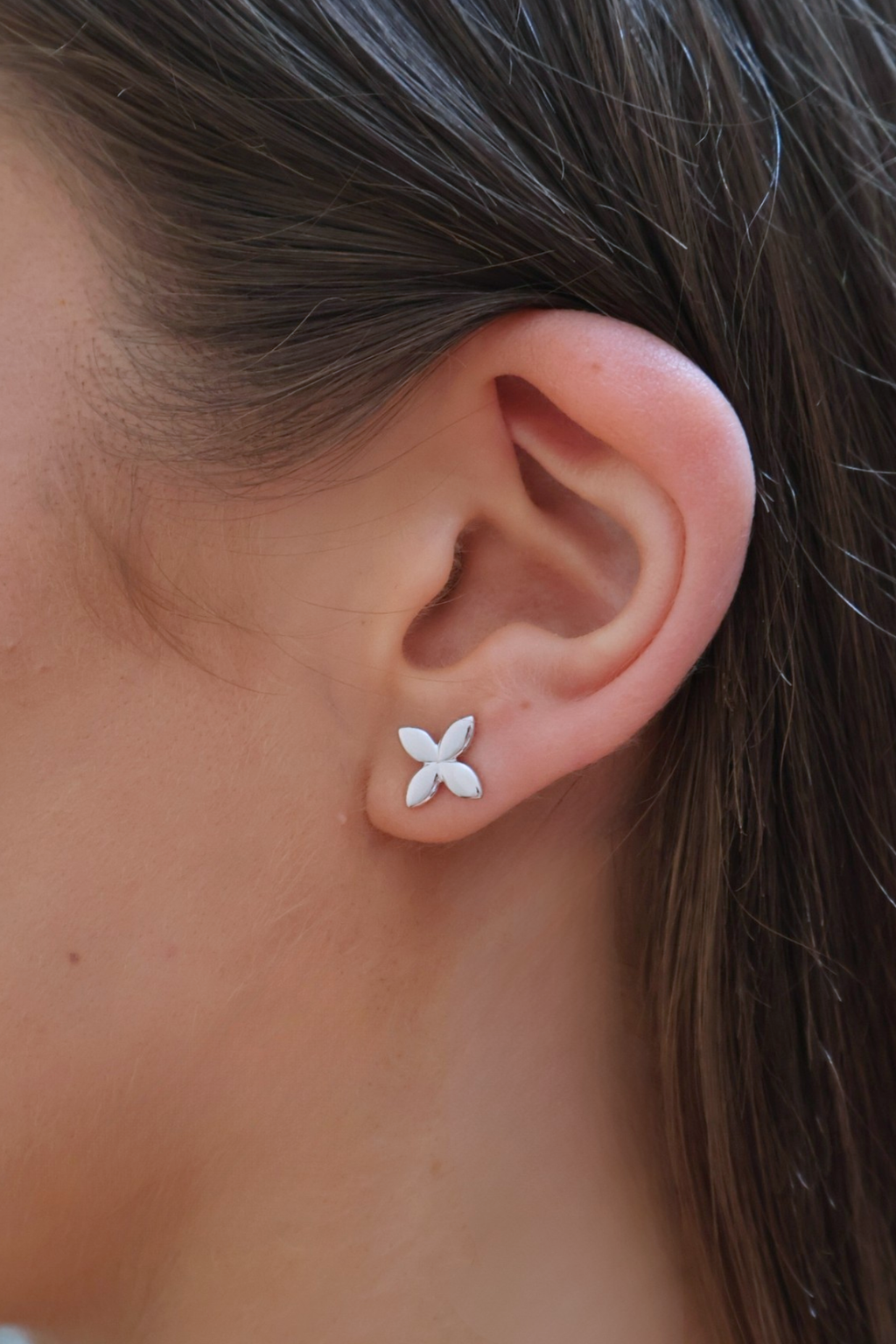 Close-up of an ear wearing a silver flower-shaped earring.