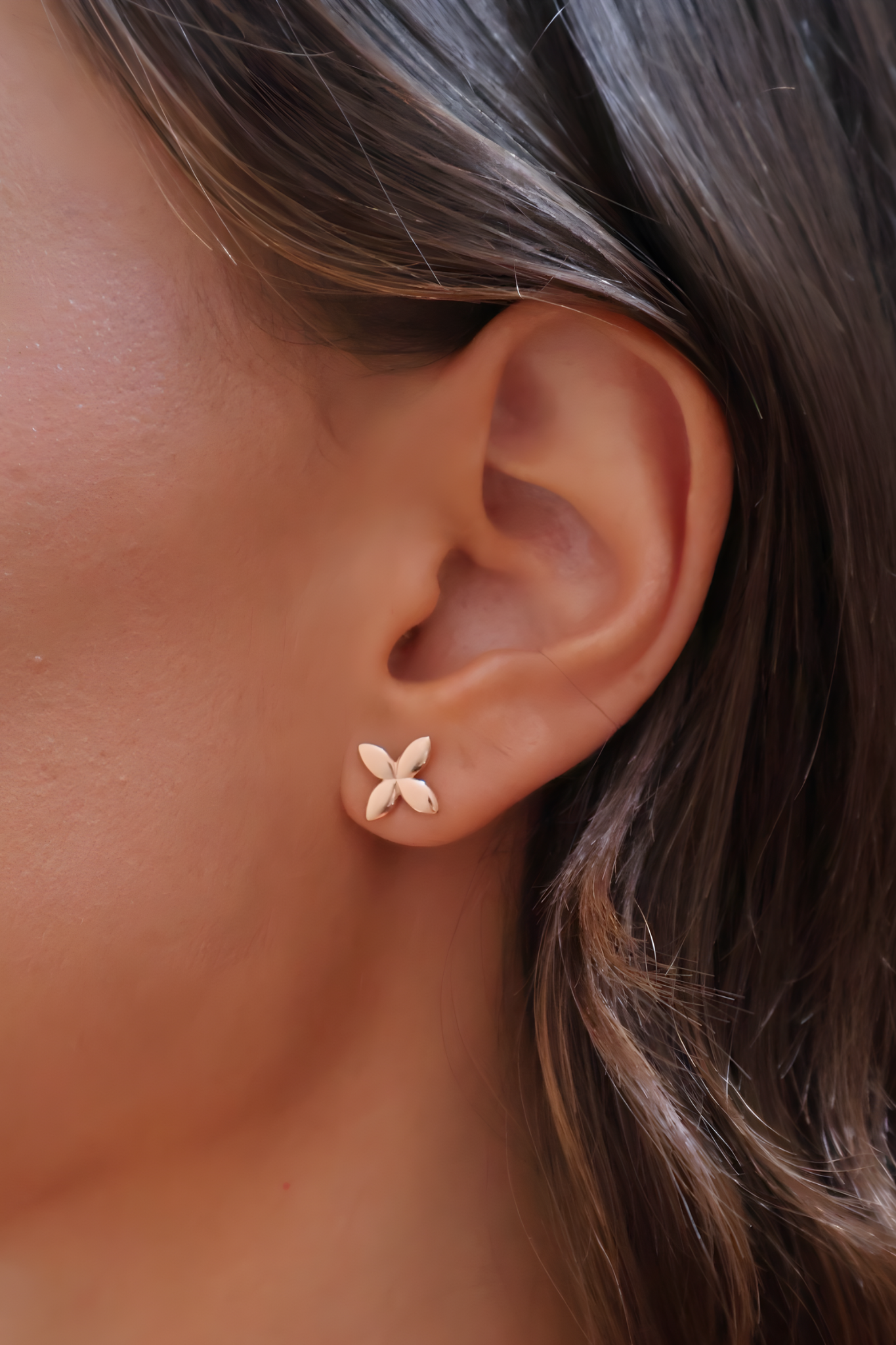 Close-up of an ear wearing a delicate flower-shaped earring.