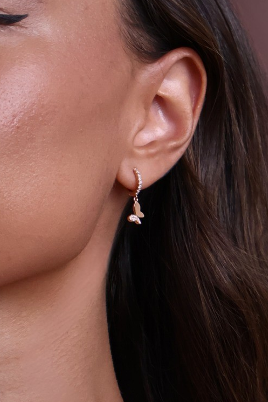 Close-up of a person wearing a delicate earring with a blurred background