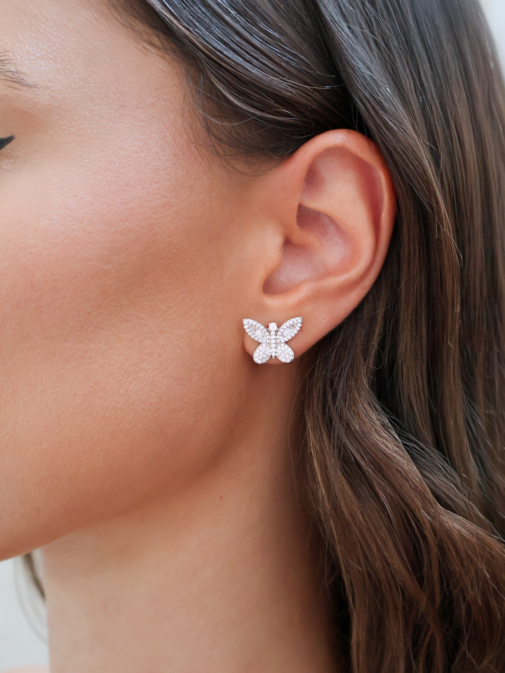 Butterfly-shaped earrings worn by a person with brown hair.