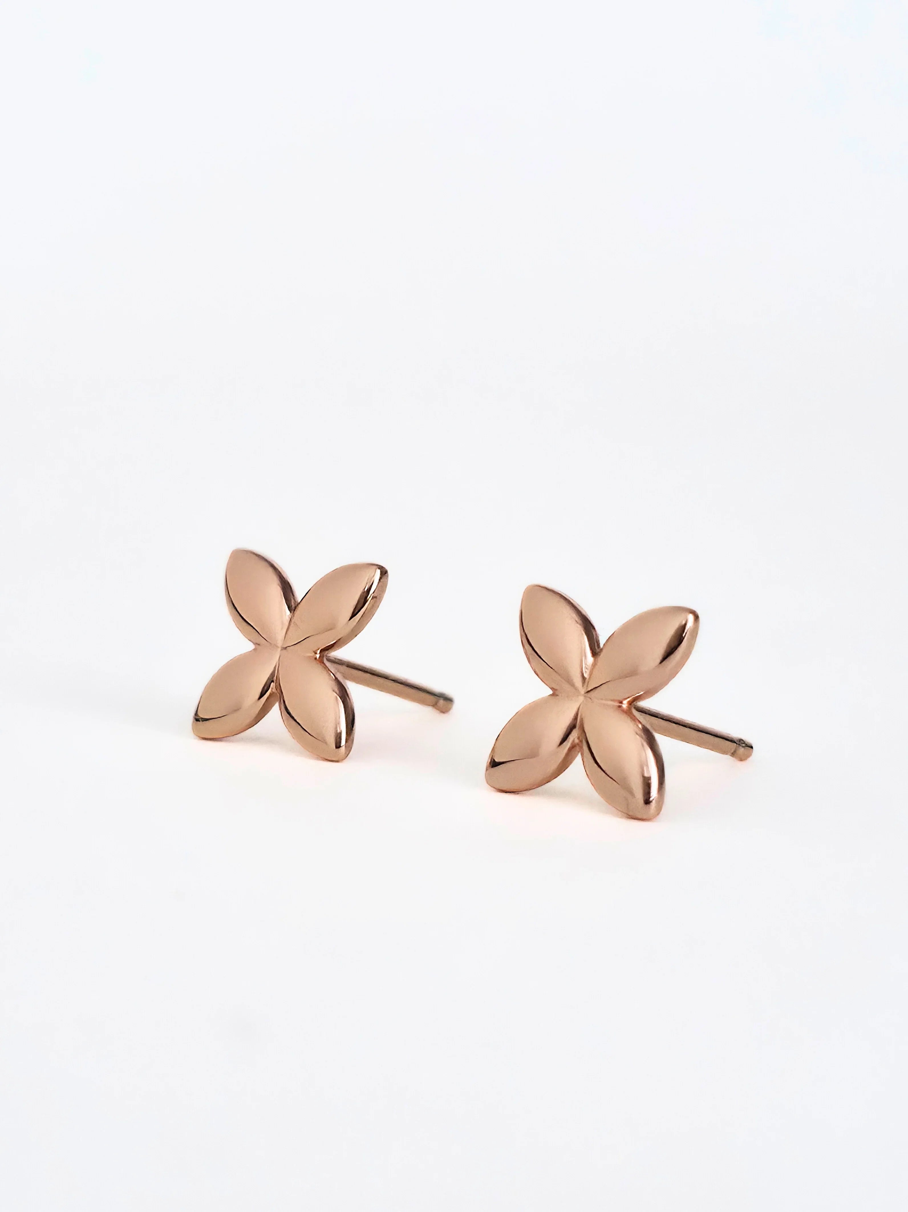 Rose gold flower-shaped earrings on a white background- a pair