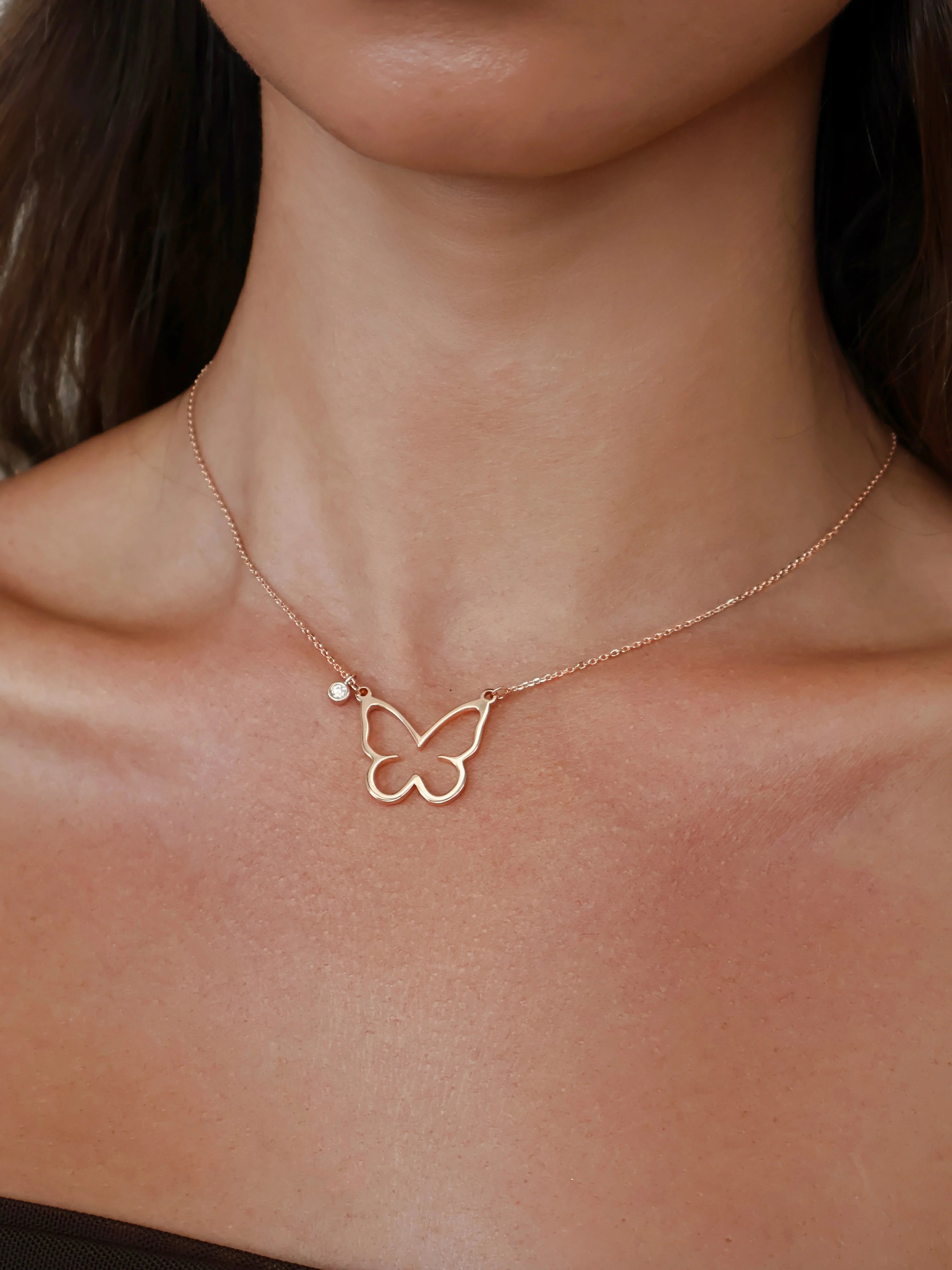 Rose gold butterfly pendant necklace with a small diamond charm on a delicate chain