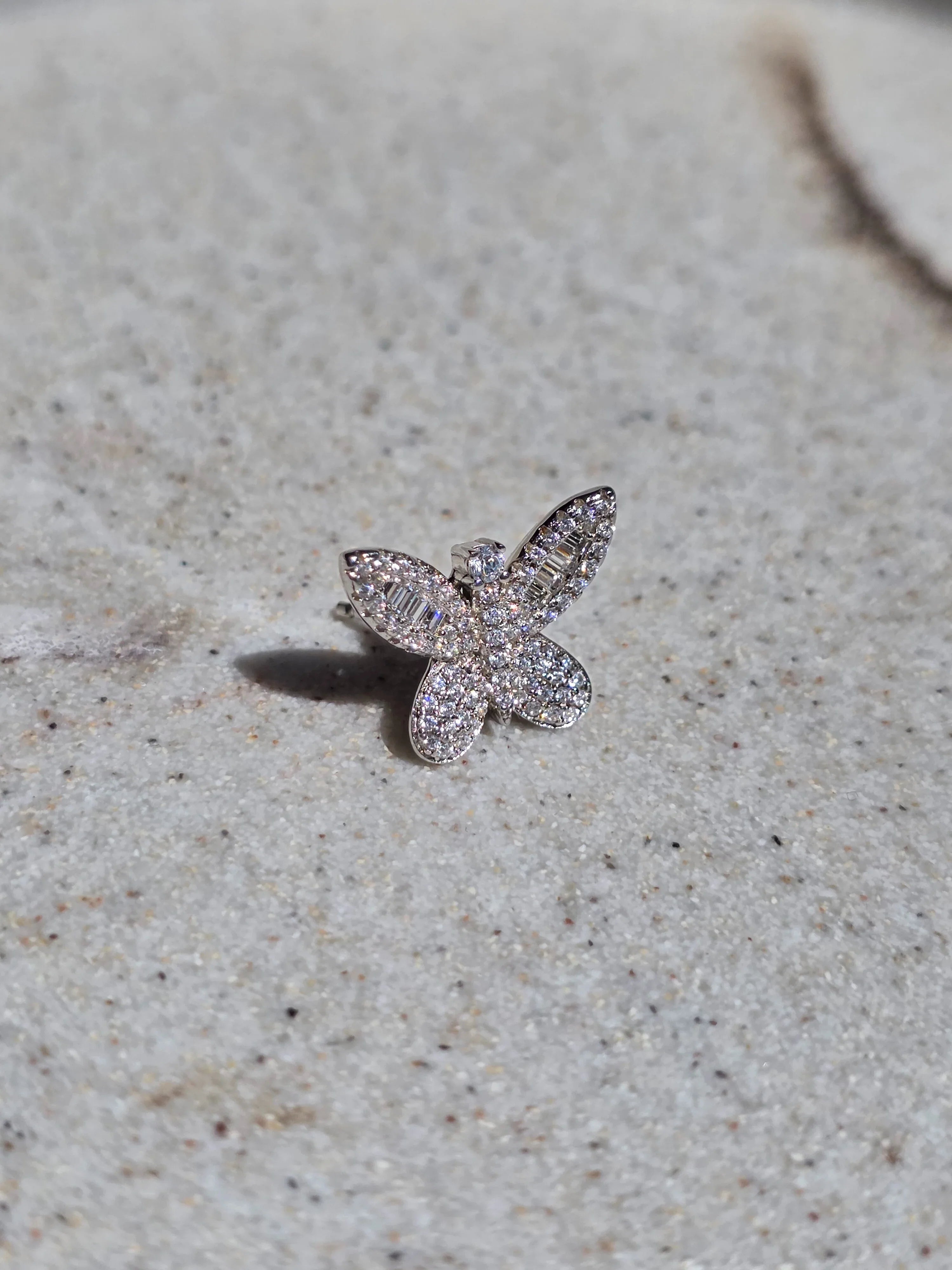 Butterfly-shaped diamond ring on a textured surface