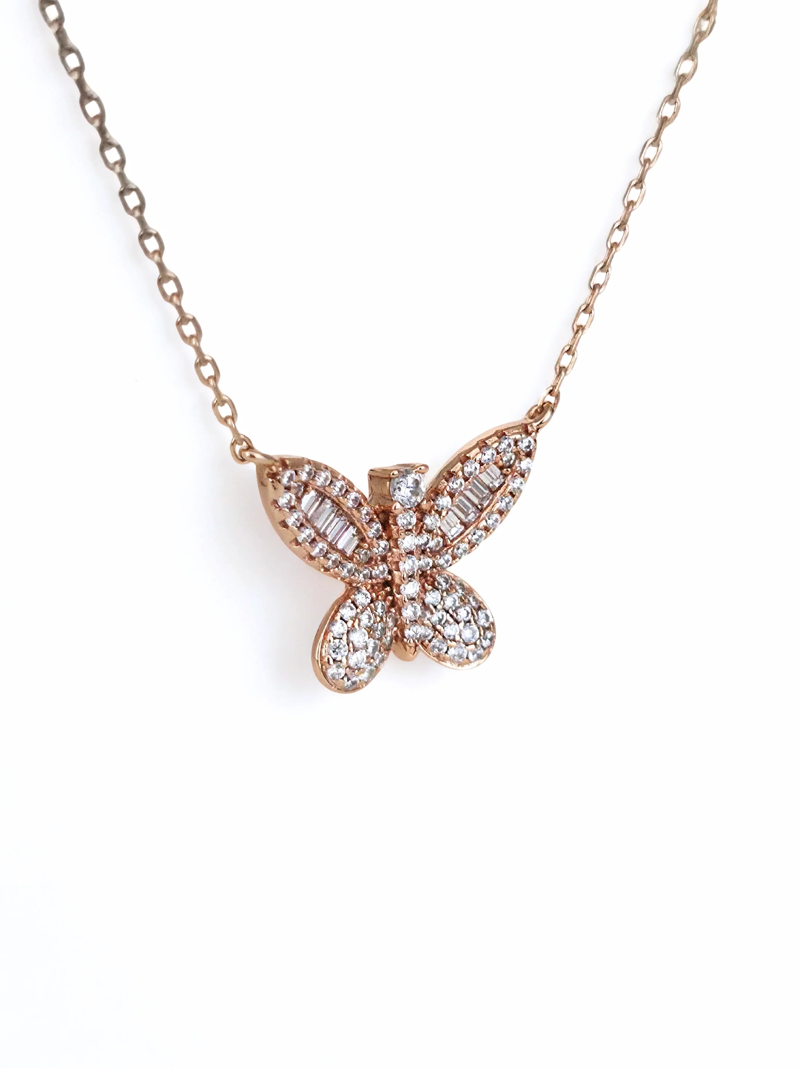 Butterfly-shaped necklace with rose gold and clear stones on a white - further background- side ways