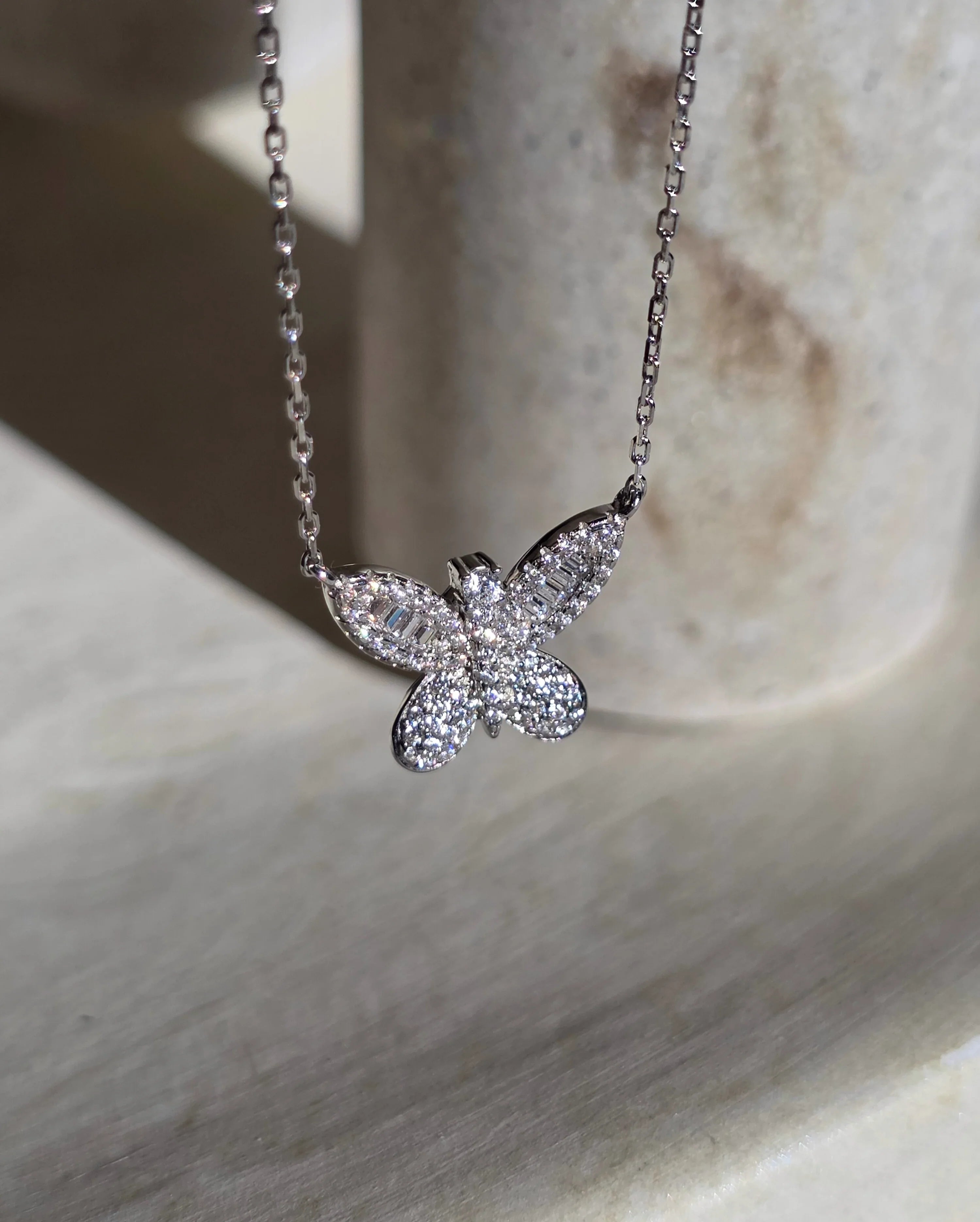 Butterfly-shaped diamond necklace on a light background- side