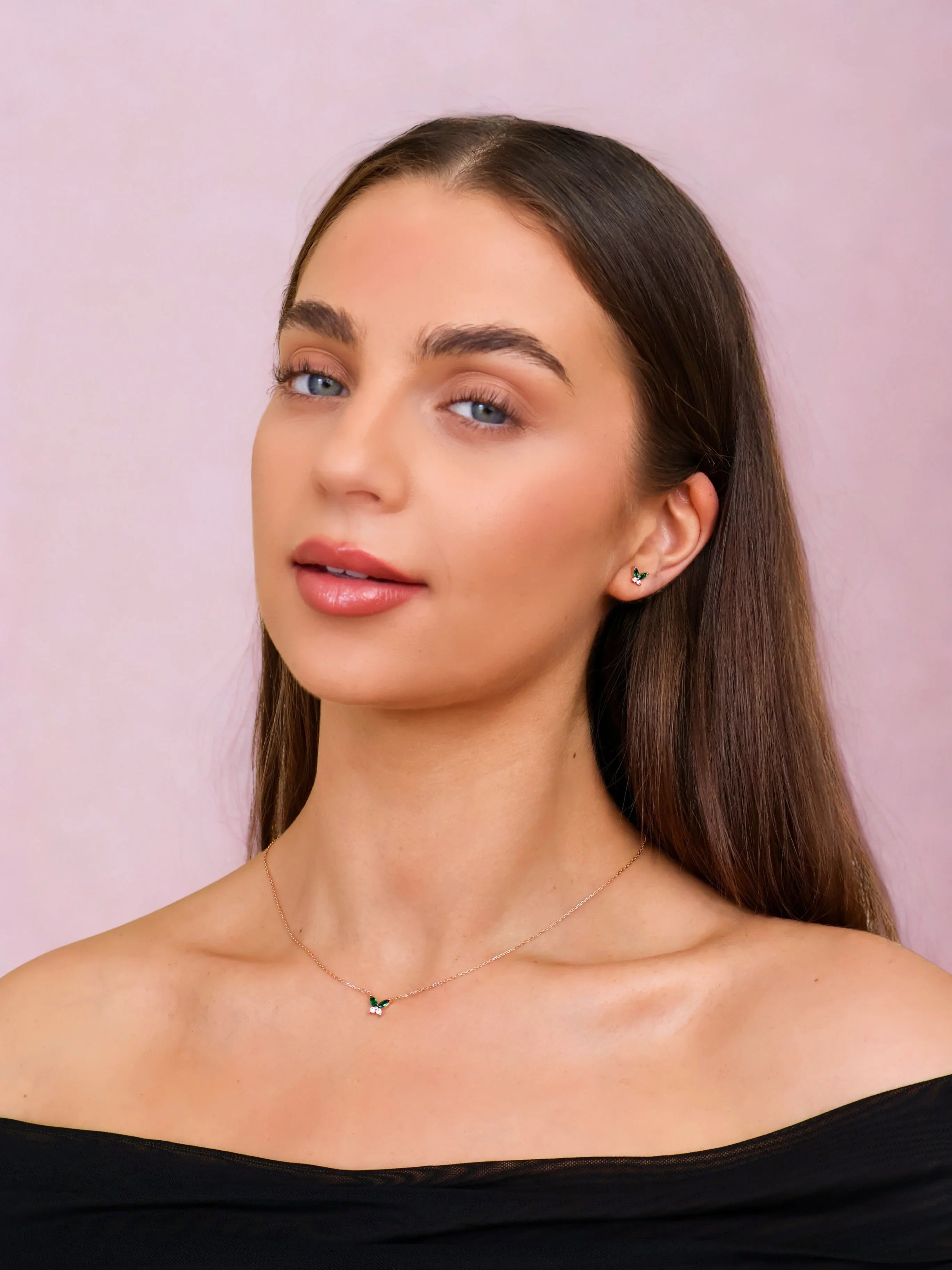 Woman wearing a delicate necklace against a pink background