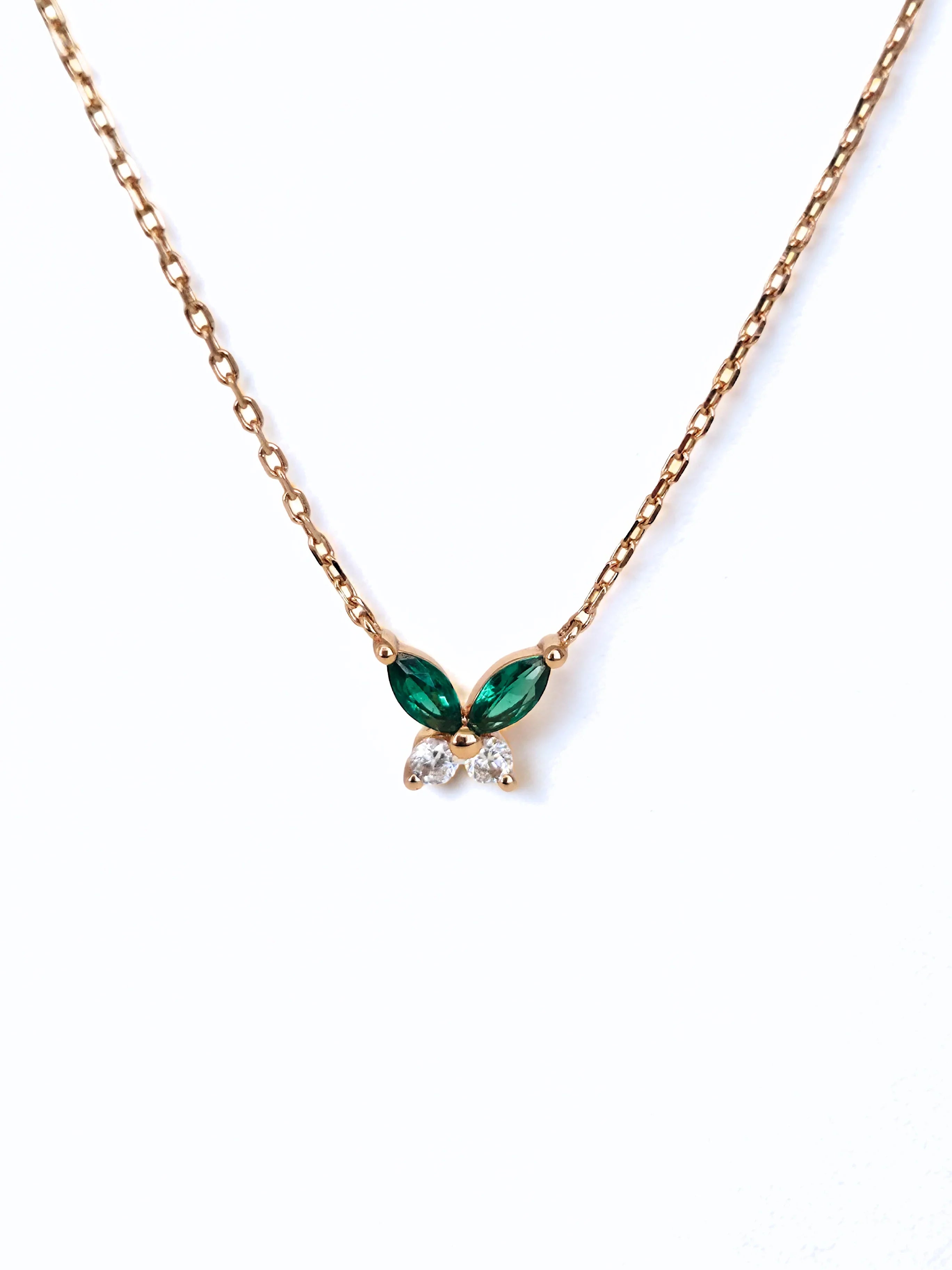Gold necklace with green gemstone butterfly pendant on a white - background front